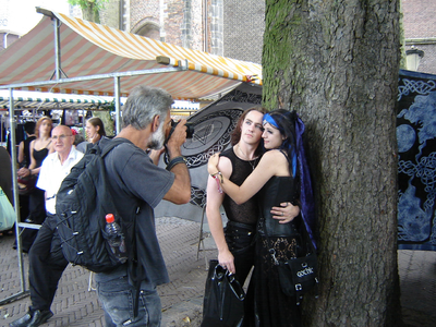 807003 Afbeelding van een fotograaf die een Gothic-jongen en -meisje fotografeert op het Domplein te Utrecht, tijdens ...